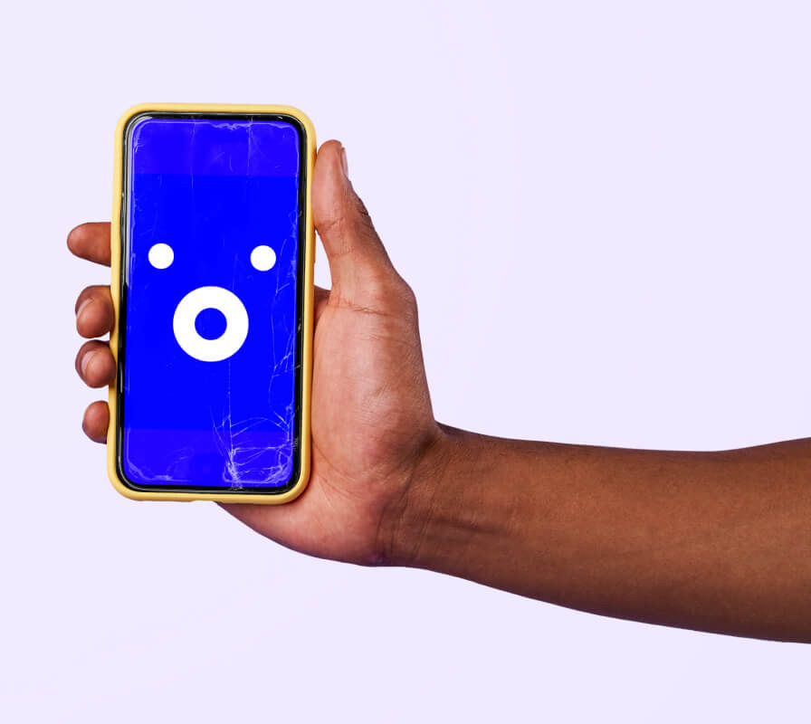 arm holding visible phone with cracked screen displaying a surprised emoji
