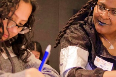 Women watching girl do school work